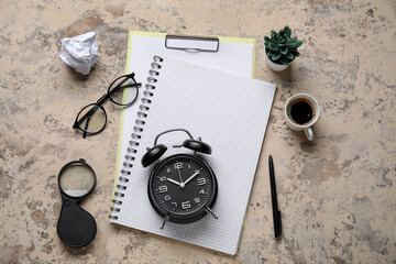 Blank notebook with eyeglasses, alarm clock and cup of coffee on grunge background