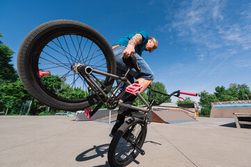 Close up of a middle-aged tattooed freestyle bmx rider performing tricks and stunts in a skate park.