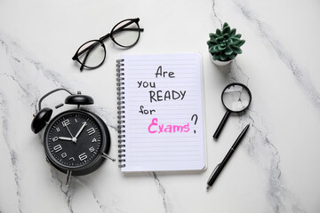 Notebook with question ARE YOU READY FOR EXAM?, alarm clock and eyeglasses on grunge white background