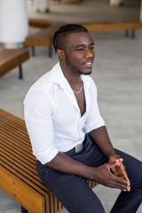 portrait of a serious african man in a white shirt on a bench	