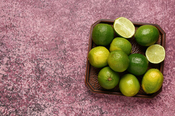 Tray with fresh limes on purple background