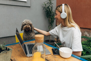 Cute dog looks at he camera while a young woman pats it.