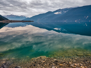 The calm surface of a clear lake surrounded by mountains in British Columbia