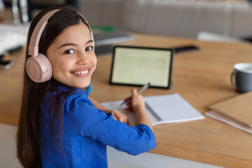 Cheerful Schoolgirl Learning Online Via Digital Tablet Sitting At Home