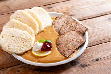 Svickova na smetane ( beef in sour cream sauce) served with knedlik (bread dumpling) on the table, traditional Czech cuisine