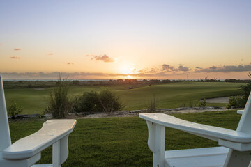 Lounge chairs, red flag and sand bunker at the beautiful golf course at the ocean side during sunrise