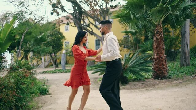 Beautiful couple practicing samba in garden. Performers dancing latino style.