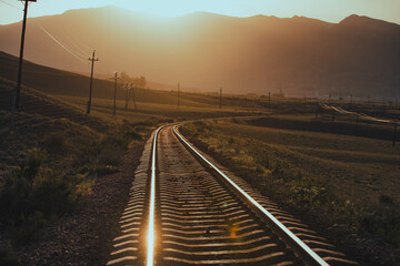 Fototapeta na wymiar Railroad in the mountains at warm sunset light
