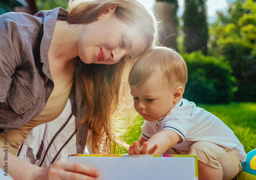 Sticker Young mother with one year child sitting in park and reading book