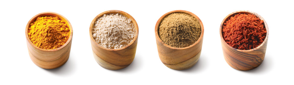 Set of powder spices in a wooden bowl isolated on white background. Wooden cup with turmeric, curry, cumin, chilli pepper, powder.