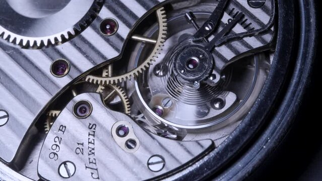 Closeup of a mechanical pocket watch balance wheel, gears, and backplate - 4K