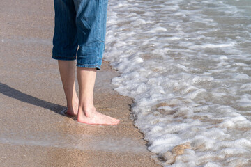 Teilaufnahme eines Mannes mit kurzer Jeanshose am Strand stehend