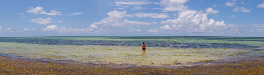 image panoramique d'une jeune femme qui se baigne dans l'océan sur une magnifique plage tropicale...