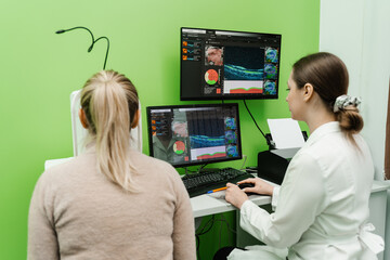 Examination of eyes of patient using optical coherence tomograph. Optical coherence tomography OCT scan to create pictures of the back of eye. Ophthalmologist is scanning cornea of woman patient.