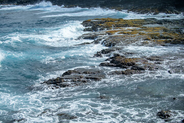 Cooled black lava beaten by the Atlantic ocean waves. View of sea waves hitting rocks on the beach. Waves and rocks.