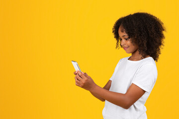 Smiling curly teen african american girl in white t-shirt typing on phone
