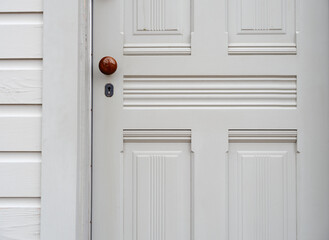 Beautifully plain white wood door with a knurled wood door knob and skeleton key lock with intricate carved wood in Old New Castle Delaware