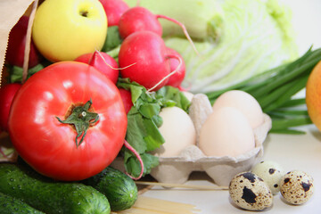online shopping, home delivery food eggs, pasta, fruits, vegetables, tomatoes, cucumbers, cabbage, radishes, apples in a paper bag