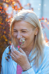 Blonde woman smiling shyly. In hand of lady white dandelion which has just blow off. Happy time...