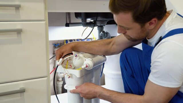 Repairman installing water filter cartridges in a kitchen. Installation of reverse osmosis water purification system
