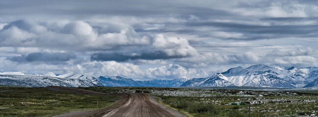 Panoramic image of Fresh July snowfall dotting the tundra and the mountains just outside the Gates of the Arctic National Park in Alaska on the Dalton Highway near Nuiqsut Alaska