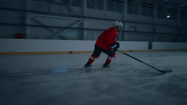 Cinematic lighting highlights a professional ice hockey player skillfully hitting, striking, and shooting the puck with a hockey stick, scoring a goal in an arena in a dramatic wide shot