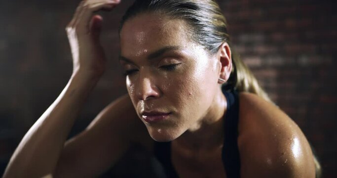 Sweating, breathing or face of a tired woman in gym for exercise workout for wellness with resilience. Fatigued girl, breathe or exhausted female sports athlete resting on break in fitness center
