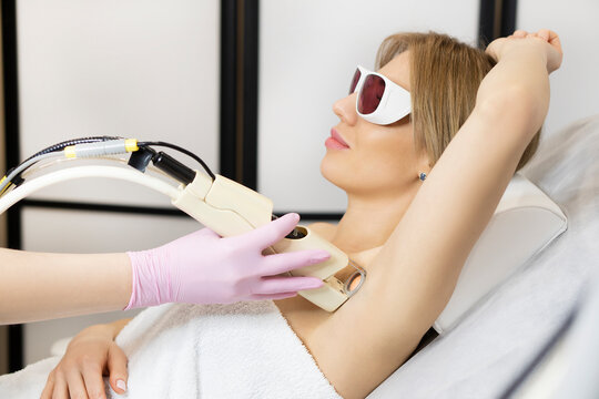 Young smiling beautiful woman getting armpit laser hair removal procedure. the concept of skin and body care in the spa salon. permanent hair removal.