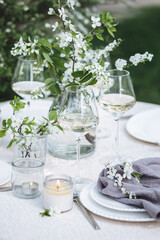 Rustic zero waste wedding decor with natural elements. Fresh spring blooming flowers, candles, linen napkins, wine glasses. Eco friendly decoration for the special holiday dinner. Romantic cozy place