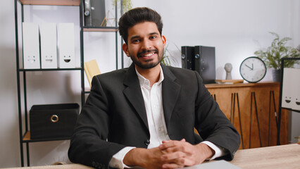 Portrait of happy smiling bearded indian businessman at modern home office workplace desk looking...