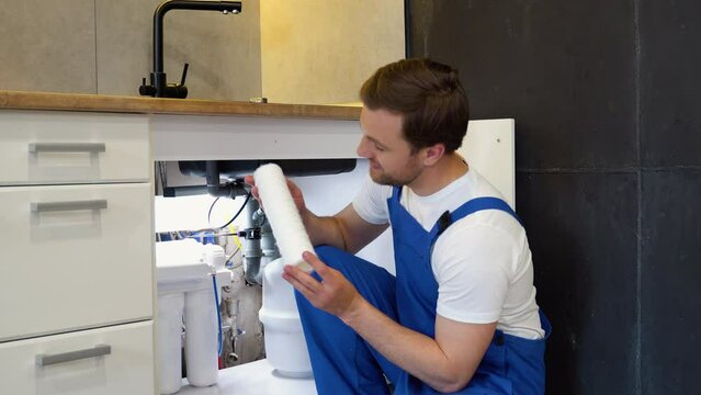 Plumber with white clean aqua filter. Serviceman change water filter. Installation of reverse osmosis water purification system