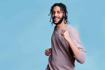 Happy handsome arab man dancing and partying while looking at camera with carefree facial expression. Young cheerful smiling person moving hands and enjoying music portrait