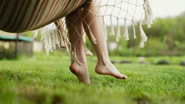 Feet of mother and child, swinging on hammock at summer. Relax, happy childhood
