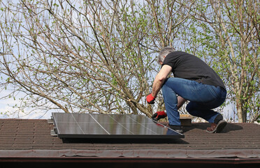 Ein Mann montiert eine kleine Solaranlage auf einem Gartenhaus