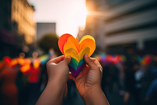Close up of hands holding a rainbow-colored paper heart, pride flag, symbolizing unity, love, and support within the LGBTQ+ community. AI Generative
