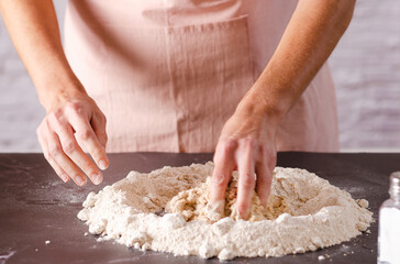 Female hands kneading dough in the kitchen, close-up. Cooking process.