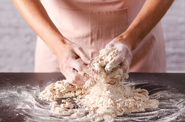 Close-up of female hands holding a bowl of flour ready to knead. Cooking process.