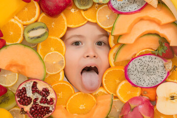 Fototapeta na wymiar Funny fruits. Kid smiling face portrait surrounded by fruits. Kids face are peeking out of the mix fruits. Open mouth, tongue out funny kids face.