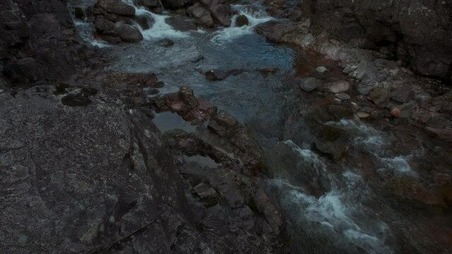 Waterfall on the rocky River Coe. 4k video with the camera moving upwards. Glencoe Mountain, Scotland, United Kingdom
