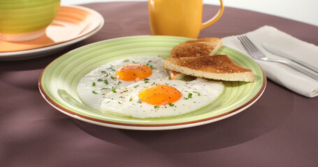 fried eggs with toast on a green plate. close-up. angle view. colored background. traditional breakfast. sunny day.