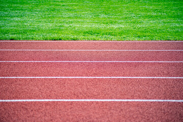 Closeup of lane lines on athletic racing track green grass background