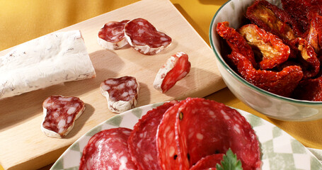 slices sausage salchichon on a plate. salami on a cutting board. cold cuts with bread and tomatoes. traditional spanish and italian sausages. meat delicacies antipasto on the table. 