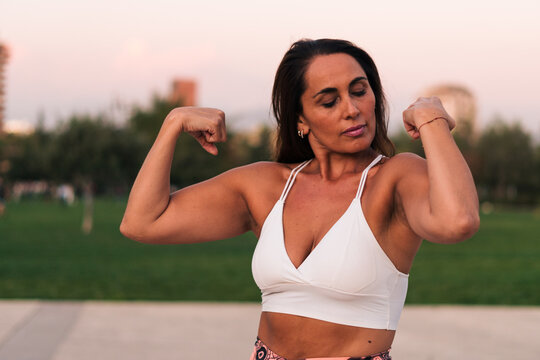 mujer adulta deportista sonriente y feliz de 40 a 50 años de edad posando y mostrando sus músculos después de hacer ejercicios.