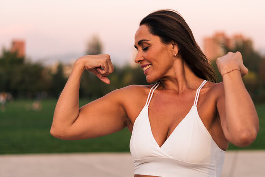 mujer adulta deportista sonriente y feliz de 40 a 50 años de edad posando y mostrando sus músculos después de hacer ejercicios.