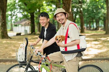 Obraz premium 飼い犬を連れて自転車で公園に来た男性2人組