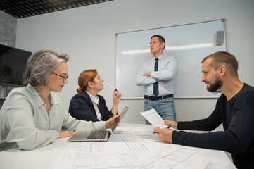 Caucasian man leading a presentation to colleagues at a white board. 