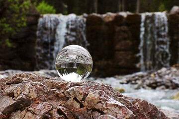 Obraz premium In einer Glaskugel spiegelt sich ein Wasserfall im Gebirge