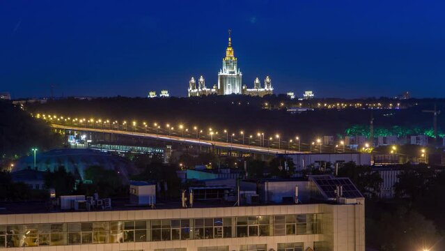 Night cityscape view of Moscow timelapse. Aerial view from rooftop to the main building of Moscow State University - one of Stalin skyscrapers illuminated at night. Traffic on the road