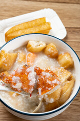 angle view spoon taking out crab from seafood porridge with deep-fried dough sticks