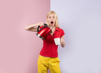 Hot beverage. Excited surprised attractive young woman housewife pouring and making tea using electric kettle for tea or coffee in color studio background. Funny girl using electric kettle.